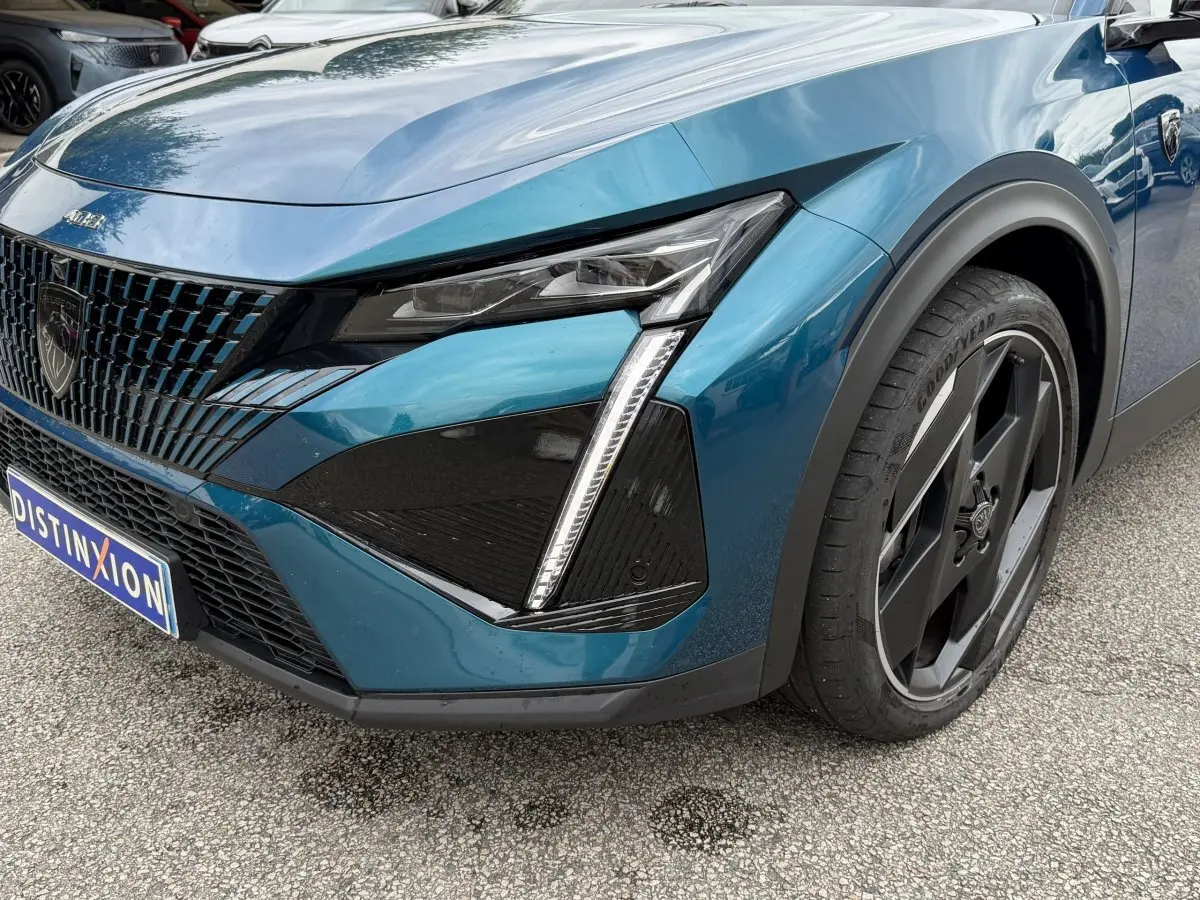 Vue 3/4 avant droit du Peugeot 408 PHEV 225 GT bleu avec phares LED et jante noire distinctive.
