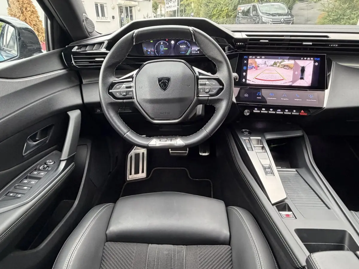 Vue intérieure frontale du poste de conduite noir du Peugeot 408 PHEV 225 GT avec écran tactile et volant multifonctions.