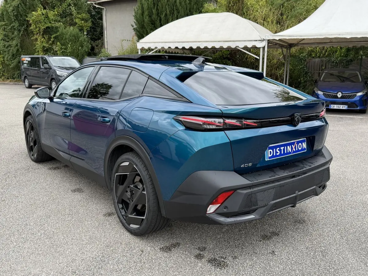 Vue 3/4 arrière droite d'une Peugeot 408 PHEV 225 GT bleu avec feux arrière LED et jantes noires distinctives.