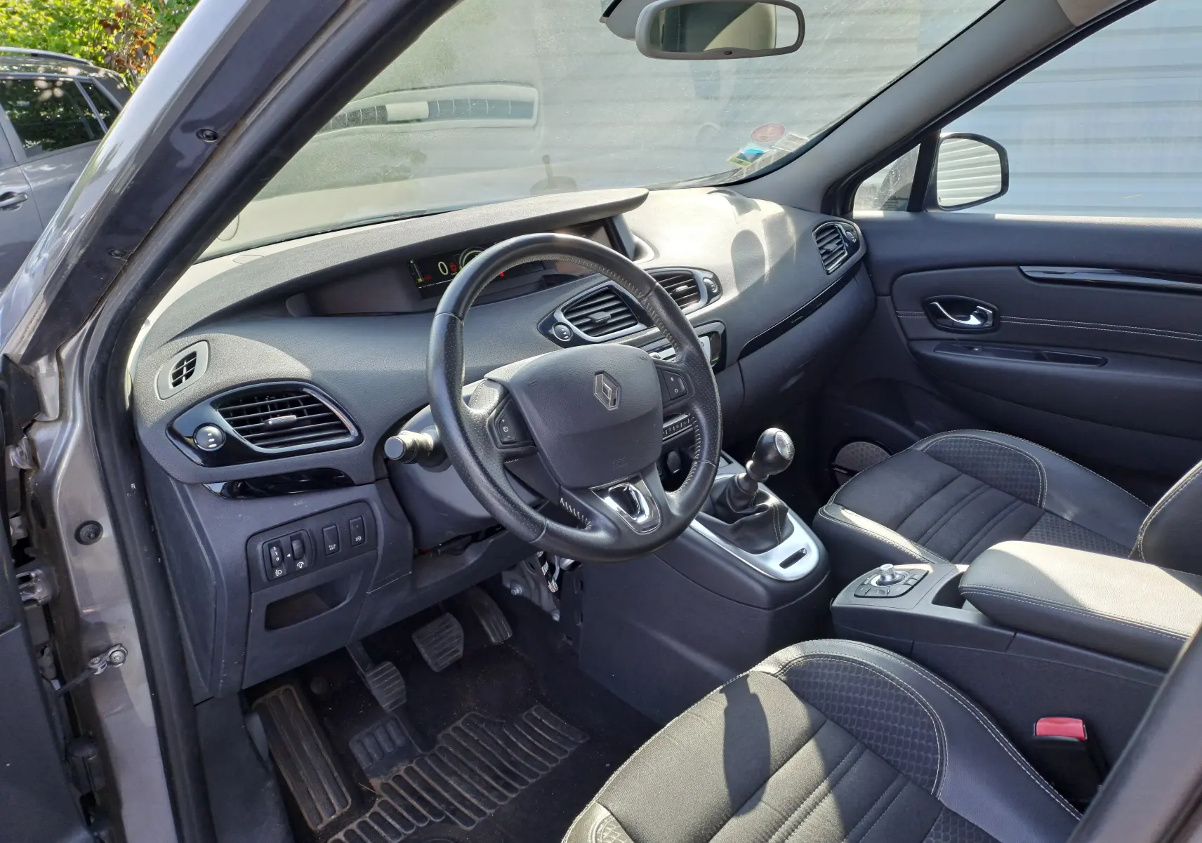 Intérieur noir du Renault Scenic III 1.2 TCE 130CH Intens, vue côté conducteur avec volant et boîte manuelle visibles.
