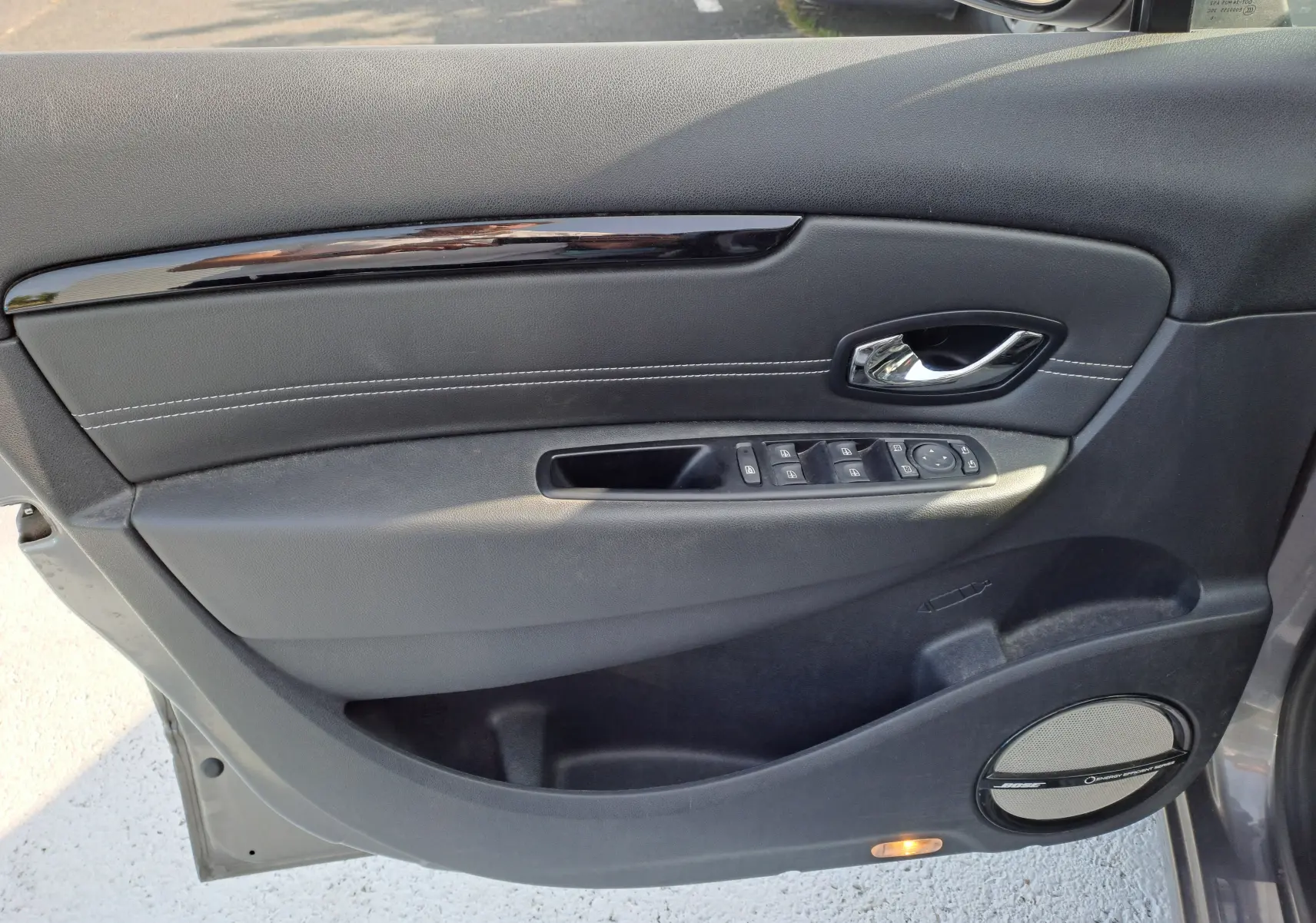 Porte avant gauche intérieure gris foncé du Renault Scénic III 2016 avec commandes de vitres et haut-parleur Pioneer.