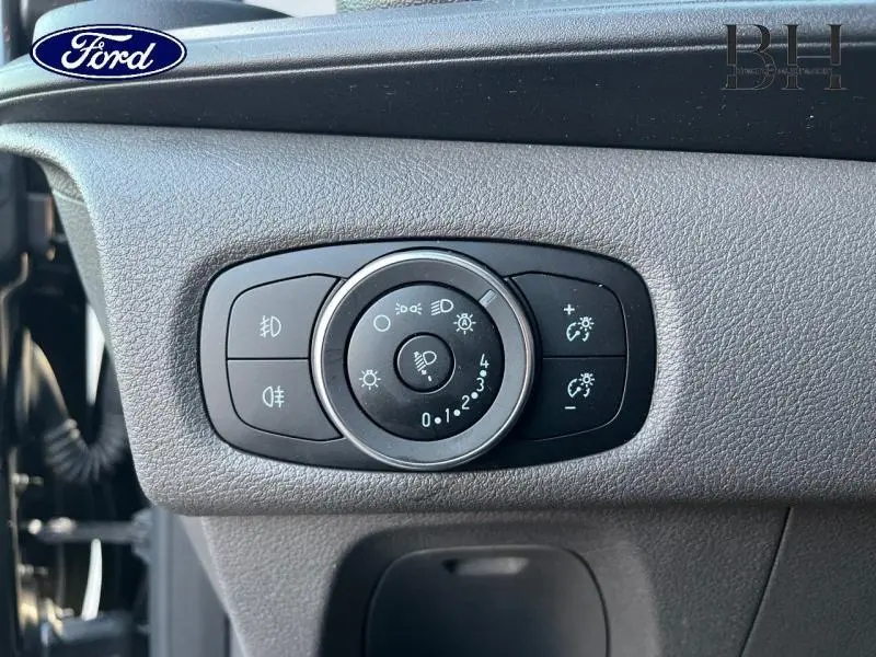 Gros plan sur le bouton de réglage des phares du Ford Transit Custom gris métallisé, intérieur tableau de bord côté gauche.