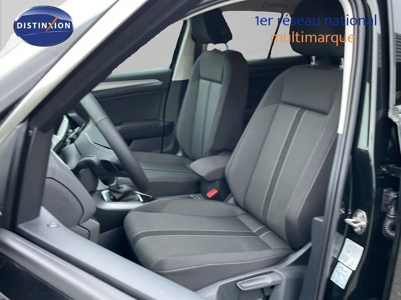 Vue intérieure côté conducteur du Volkswagen T-Roc noir Grenadilla, mettant en valeur les sièges en tissu gris et la console centrale.