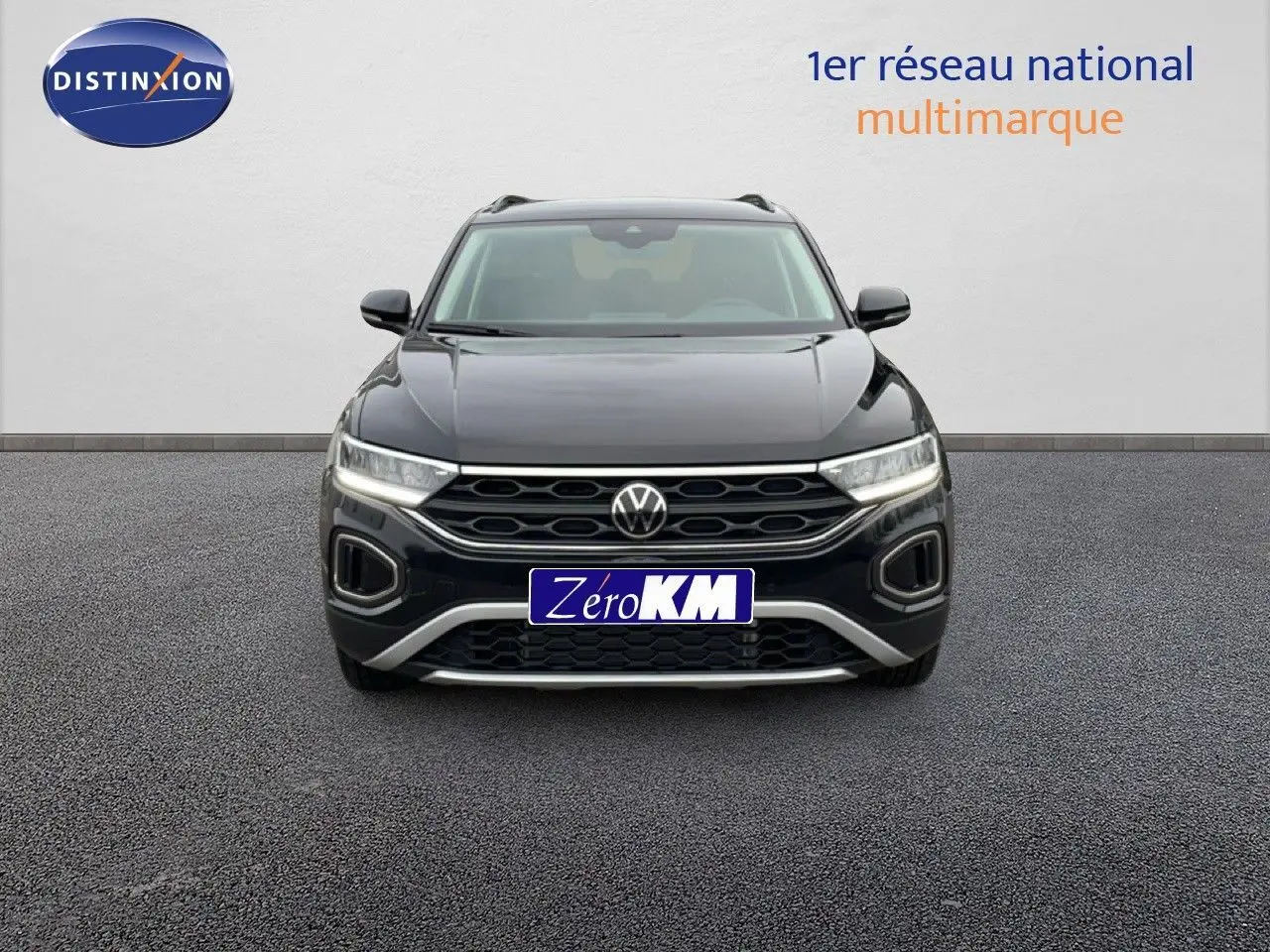 Vue frontale d'un Volkswagen T-Roc noir grenadilla métallisé avec calandre hexagonale et phares LED allumés.