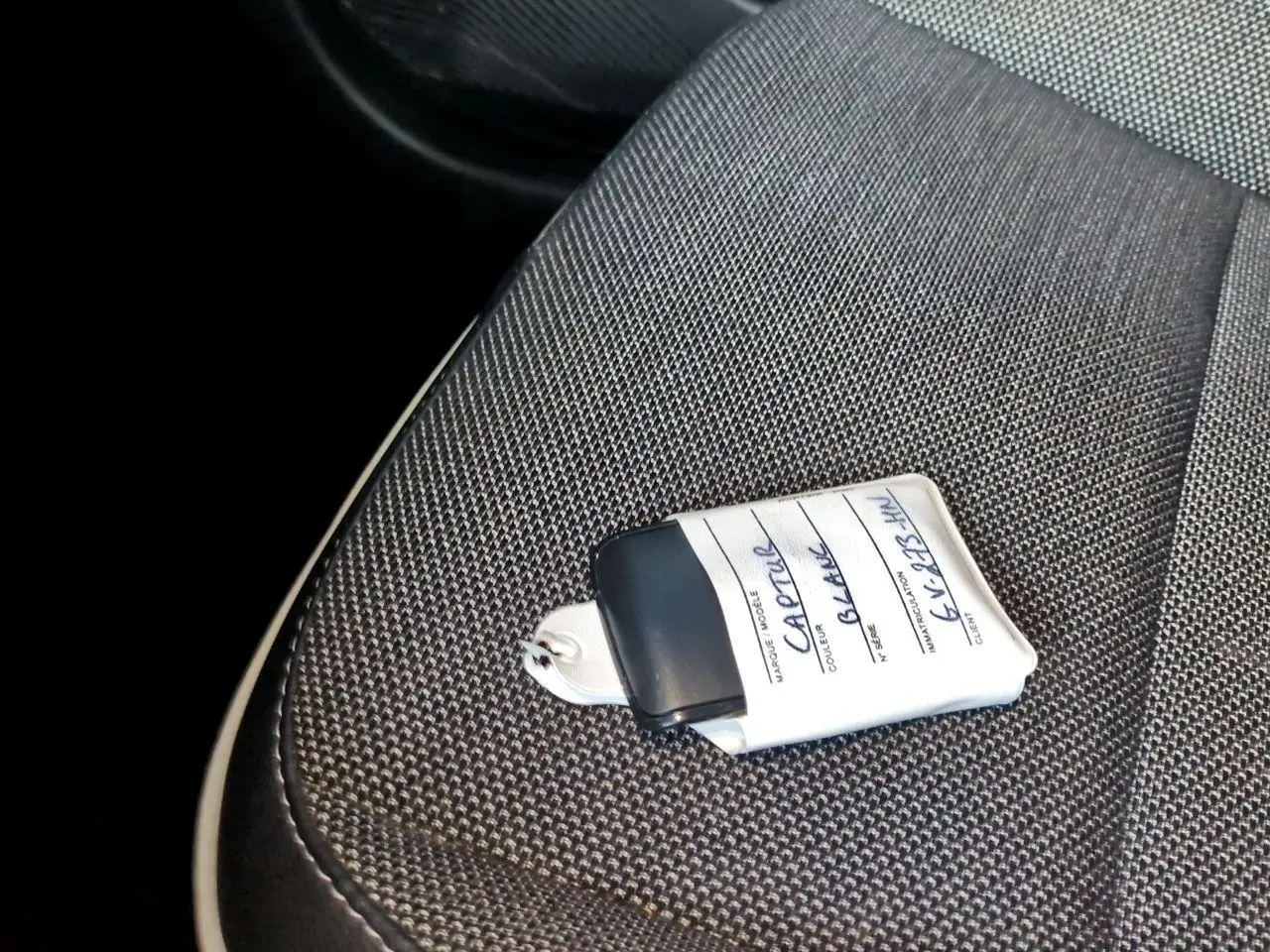 Gros plan sur la clé blanche posée sur le siège tissu gris foncé de la Renault Captur 2024.