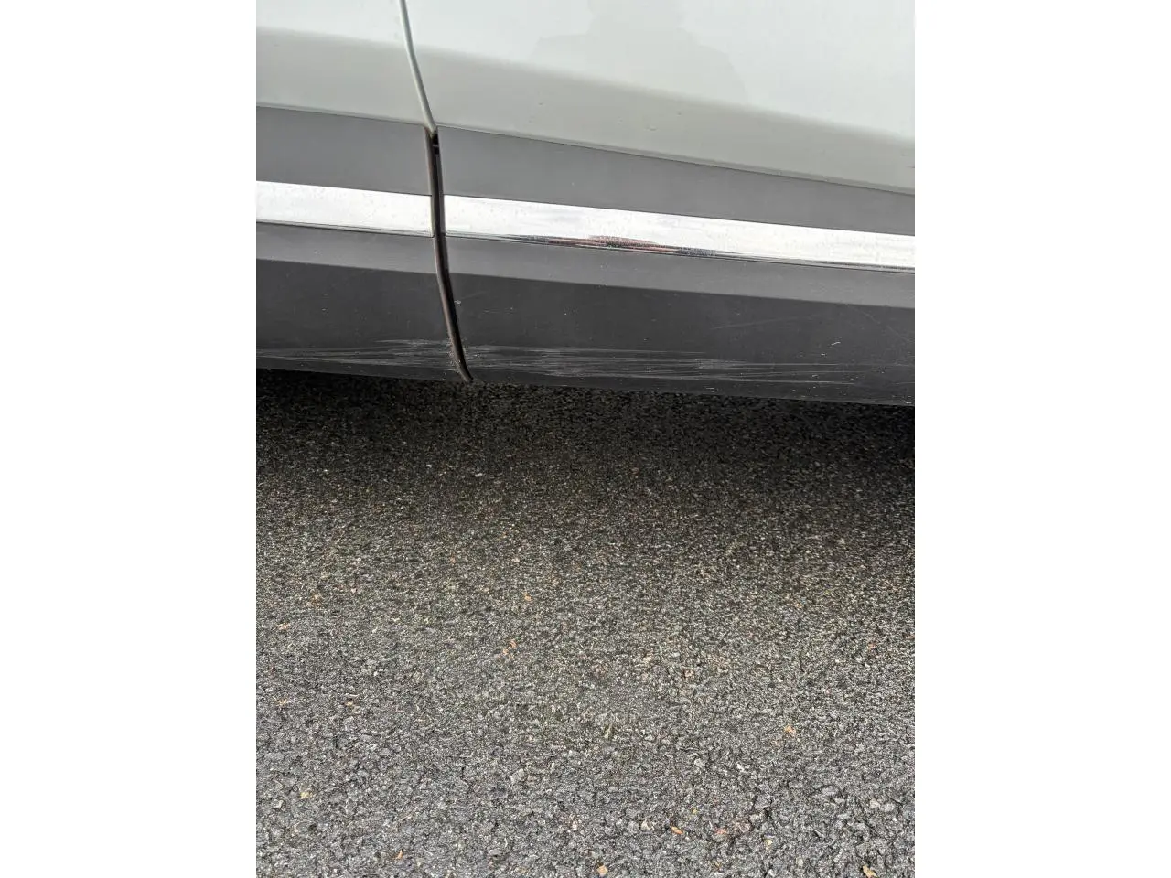 Gros plan sur la partie basse côté droit d’un Renault Captur blanc avec rayures visibles sur le bas de caisse.