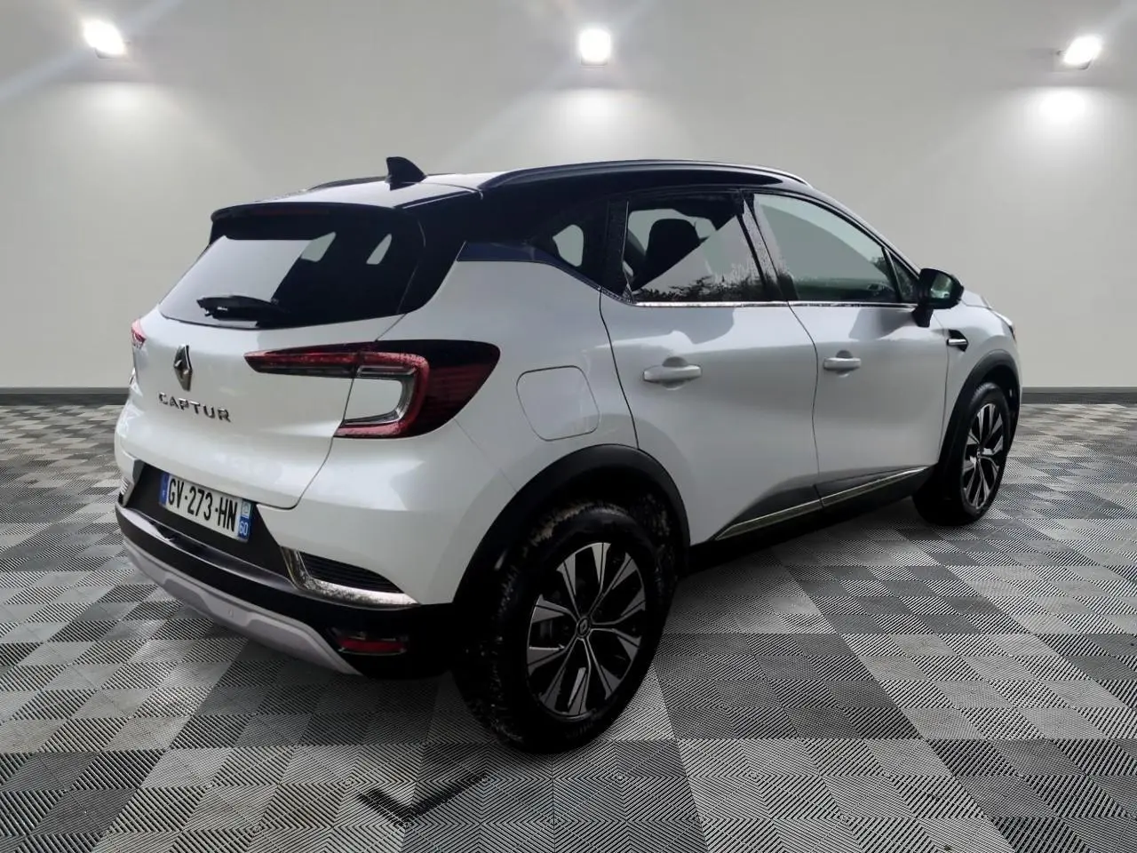 Vue 3/4 arrière droite d’un Renault Captur blanc 2024 avec toit noir et jantes alliage bicolores.