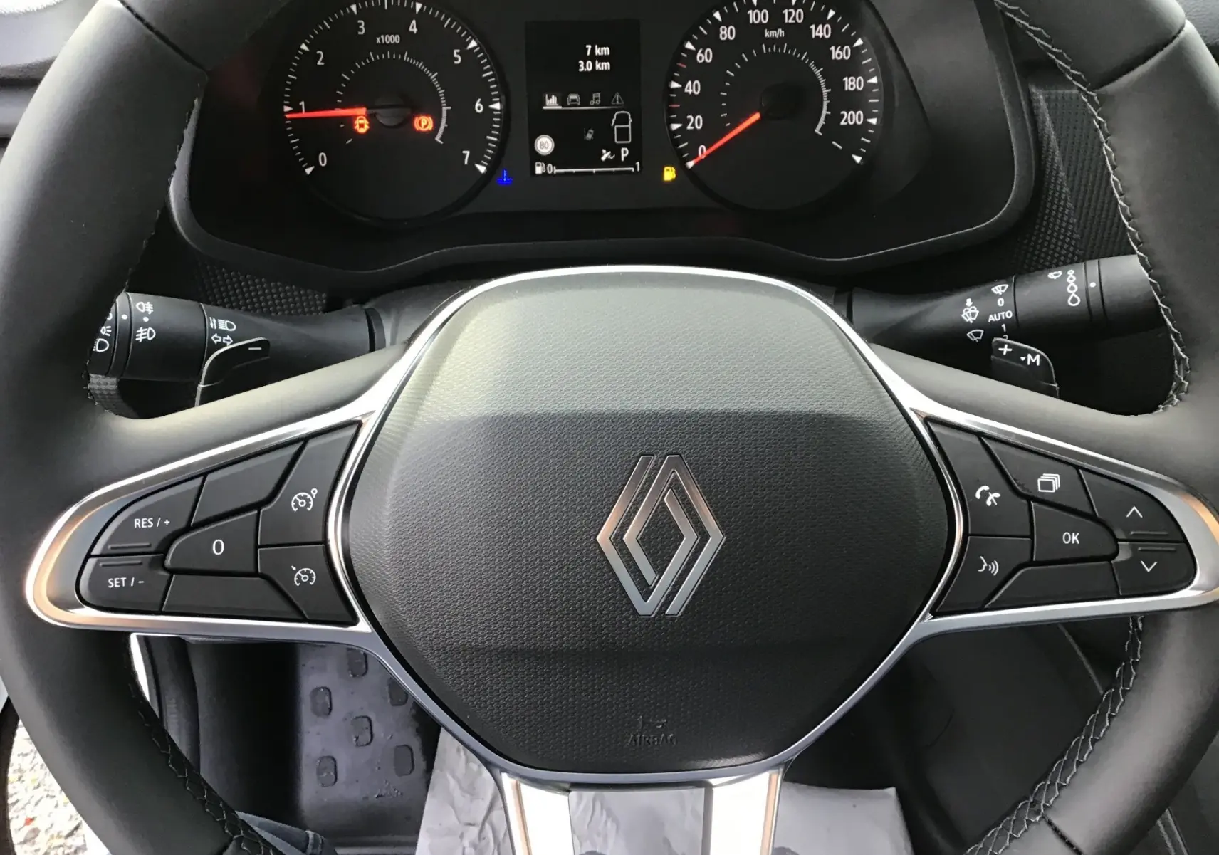 Vue rapprochée du volant noir du Renault Trafic Fourgon 2025 avec commandes intégrées et tableau de bord digital.