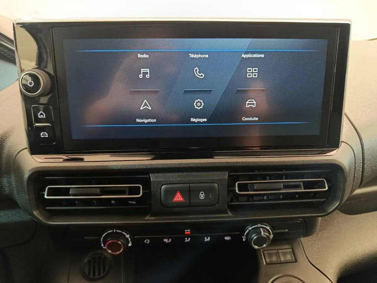 Écran tactile central du Peugeot Partner 2025 avec commandes climatisation et boutons d’alerte, vue de face.