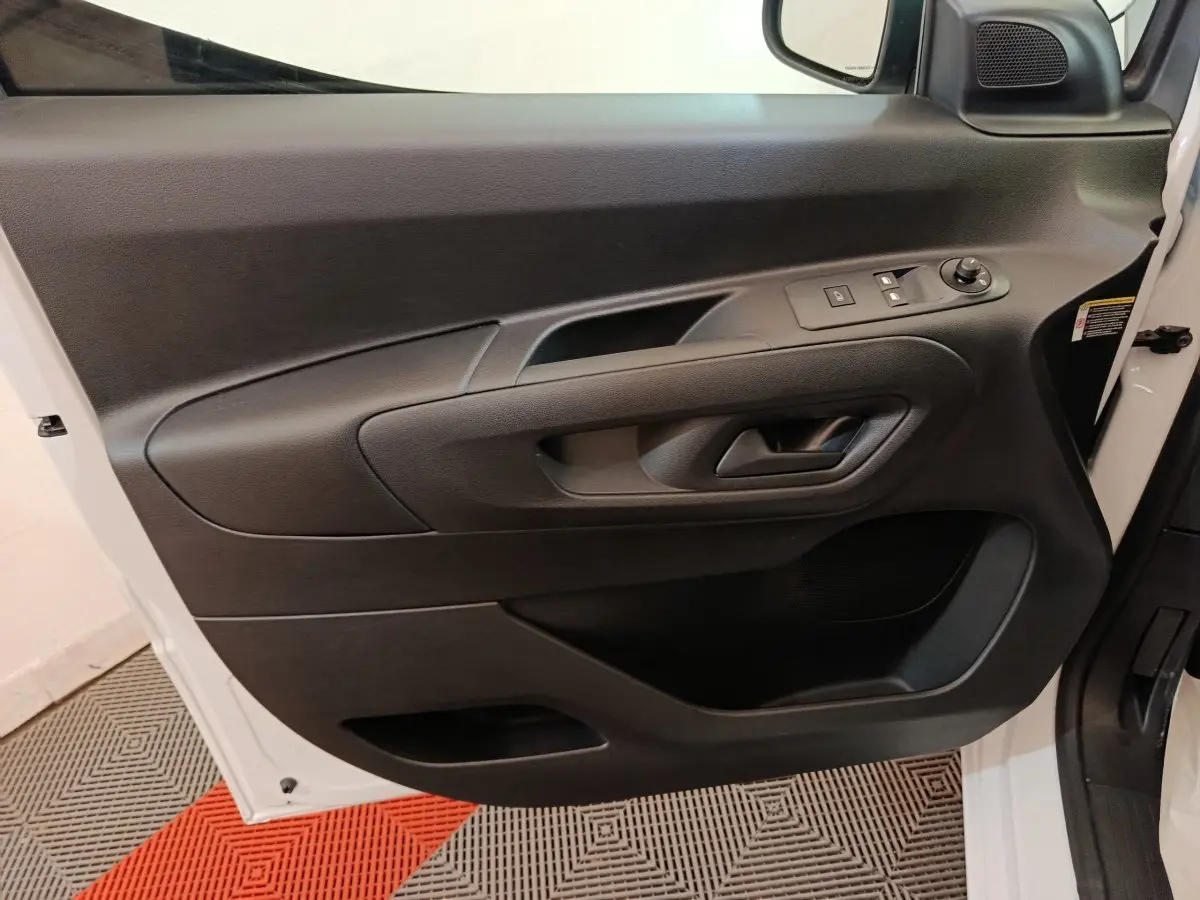 Vue rapprochée de la porte avant gauche blanche du Peugeot Partner 2025 avec commandes électriques et poignée noire intégrée.
