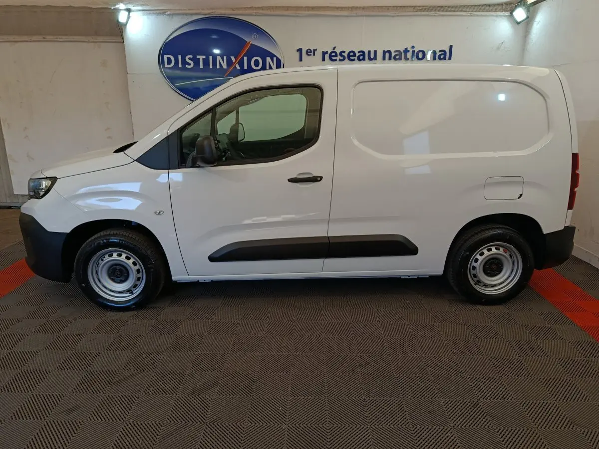 Peugeot Partner blanc en vue de profil côté gauche, utilitaire compact avec porte latérale pleine et jantes acier.