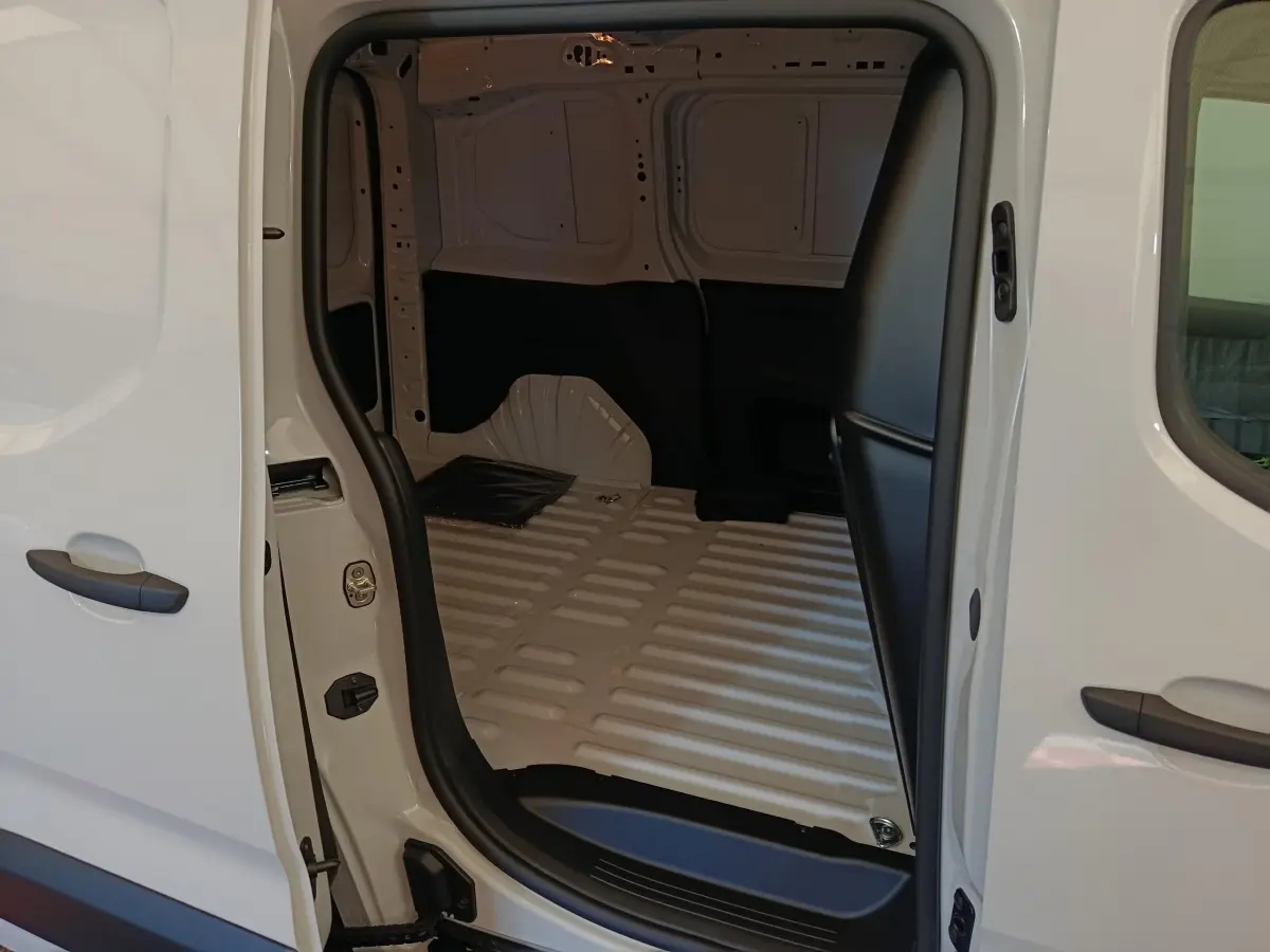 Vue intérieure côté droit du coffre blanc du Peugeot Partner 2025, montrant l’espace de chargement vide et la cloison pleine.