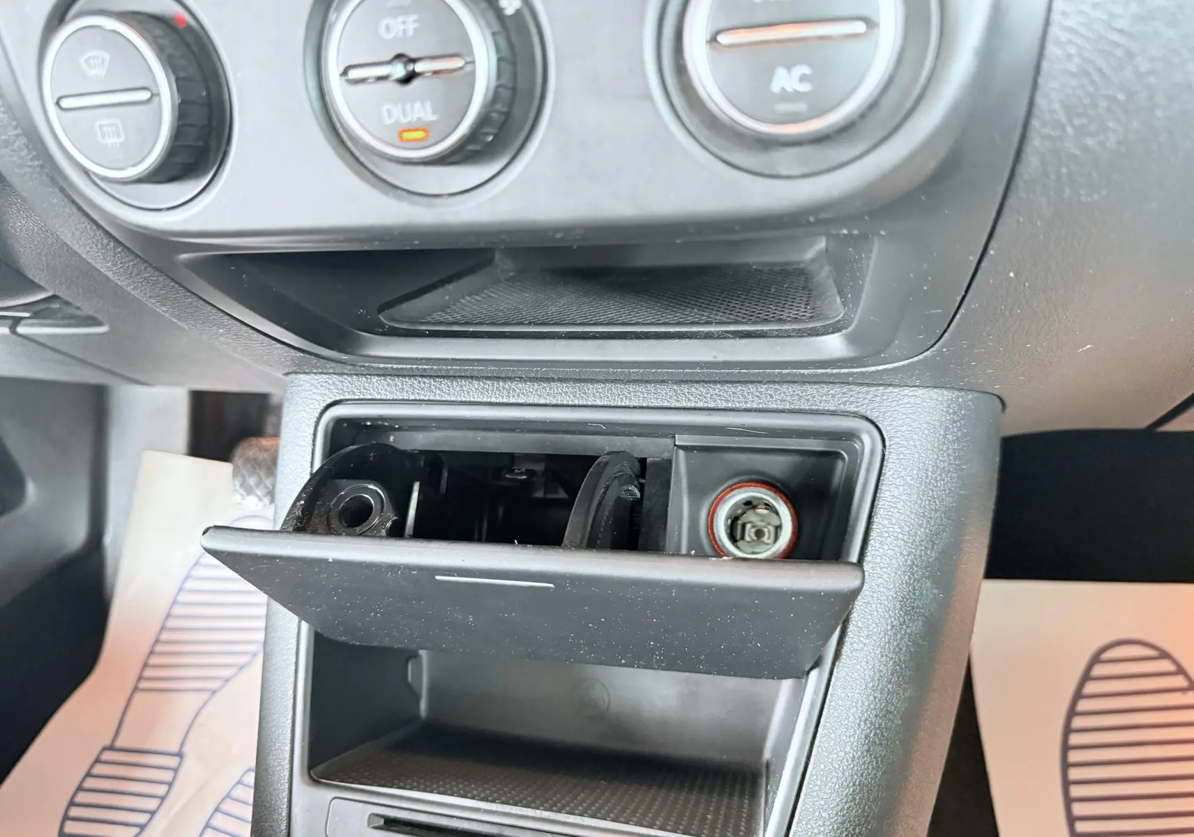 Détail de la console centrale noire du Volkswagen Tiguan 2007, avec cendrier ouvert et commandes de climatisation visibles.