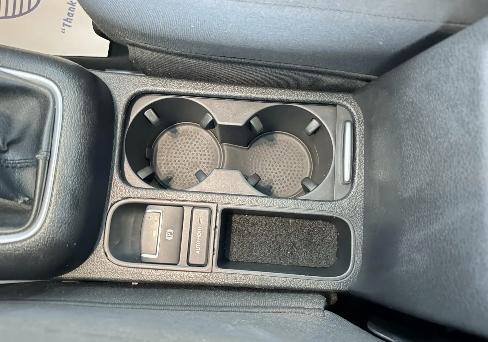 Gros plan sur la console centrale avec porte-gobelets et commandes électroniques dans un Volkswagen Tiguan noir.