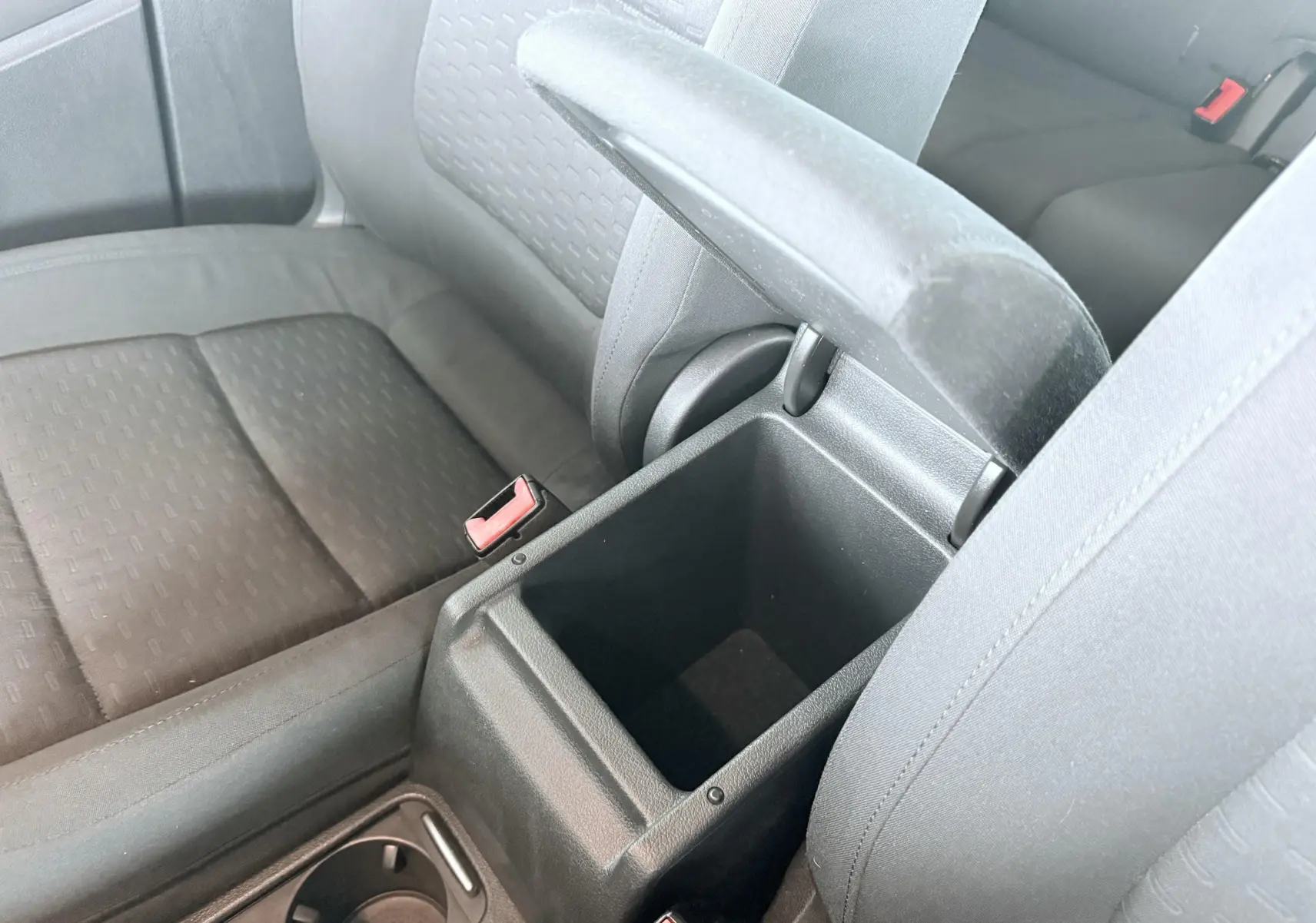Vue intérieure rapprochée du coffre central ouvert entre les sièges avant noirs en tissu du Volkswagen Tiguan 2007.