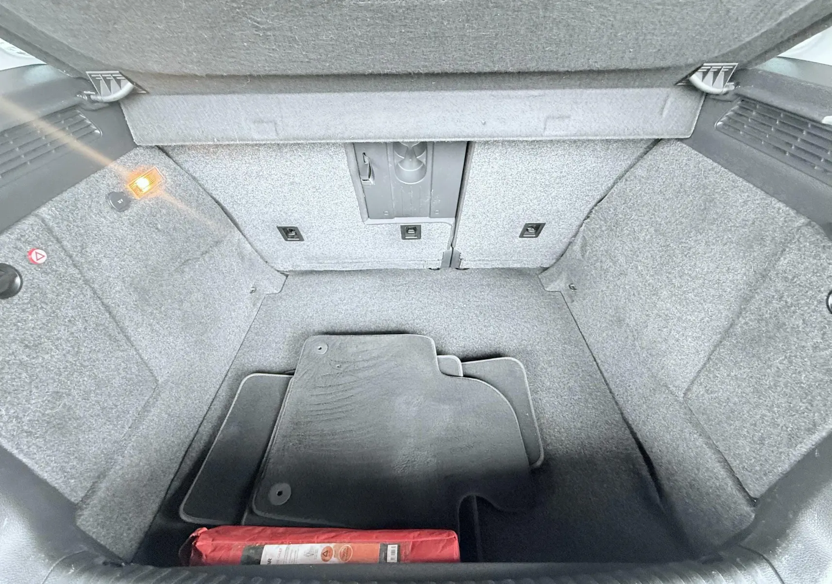 Vue intérieure du coffre gris clair du Volkswagen Tiguan 2007 avec tapis et triangle de sécurité rouge.