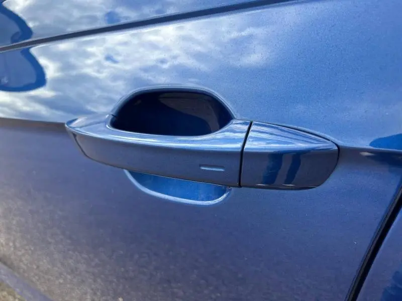 Poignée de porte côté gauche bleu récif métallisé du Volkswagen Taigo 1.5 TSI R-Line 2023 avec capteur tactile intégré.