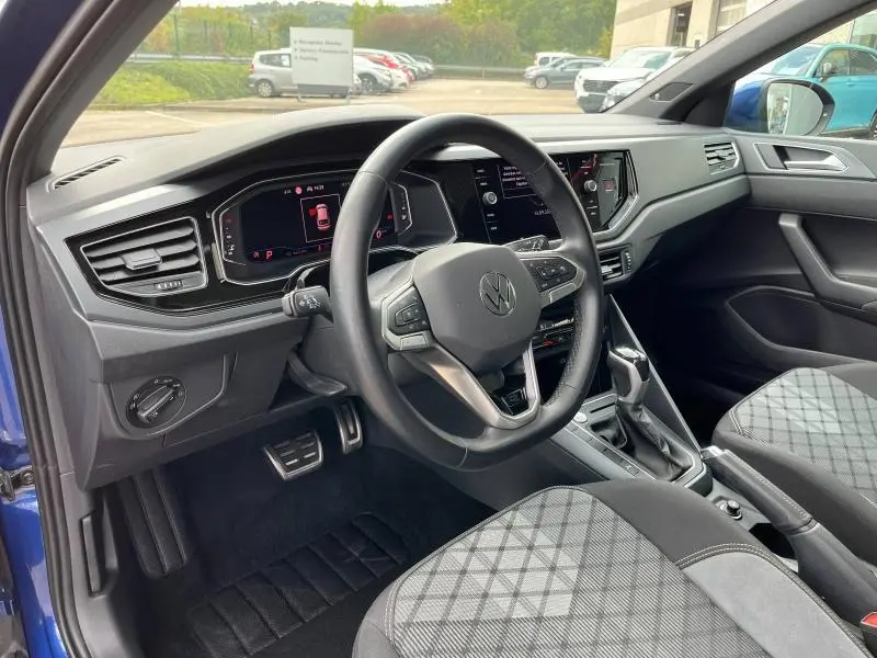 Intérieur côté conducteur du Volkswagen Taigo bleu récif 2023, volant cuir multifonction et tableau de bord digital.