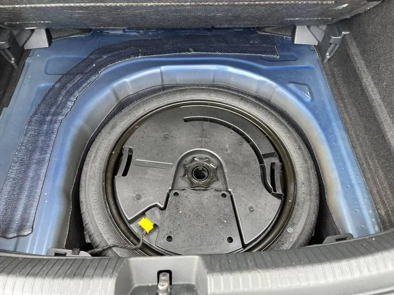 Vue plongeante sur la roue de secours dans le coffre bleu récif métallisé du Volkswagen Taigo 1.5 TSI R-Line 2023