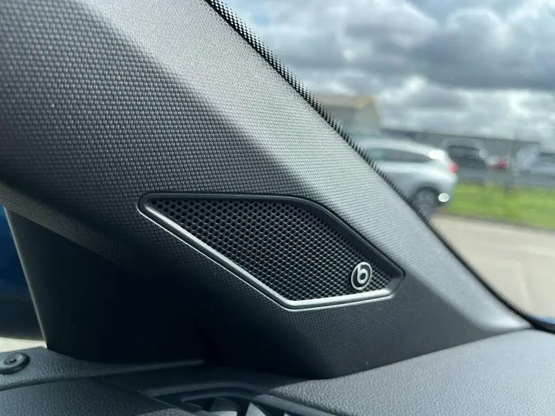 Gros plan sur haut-parleur Beats Audio intégré côté gauche du tableau de bord d'un Volkswagen Taigo bleu récif 2023.