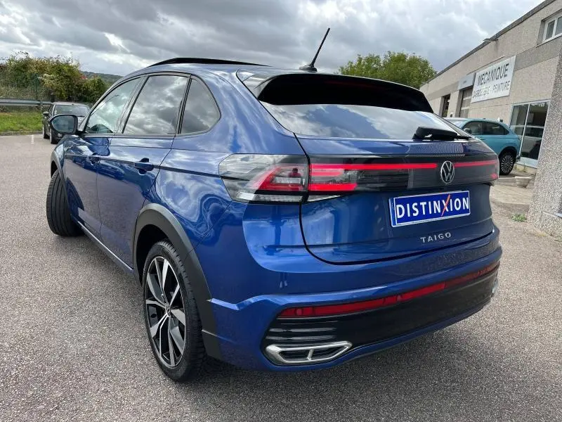 Vue 3/4 arrière droite d'un Volkswagen Taigo bleu récif métallisé avec feux arrière LED et jantes alliage noires et argentées.