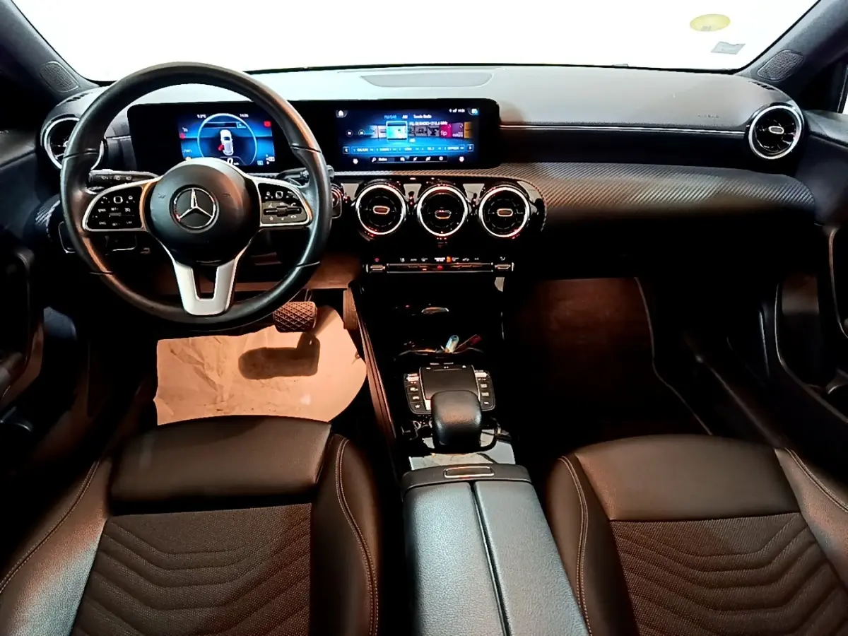 Vue intérieure avant de la Mercedes Classe A 180 d Business Line 2021, tableau de bord noir avec écran tactile et volant cuir multifonctions.