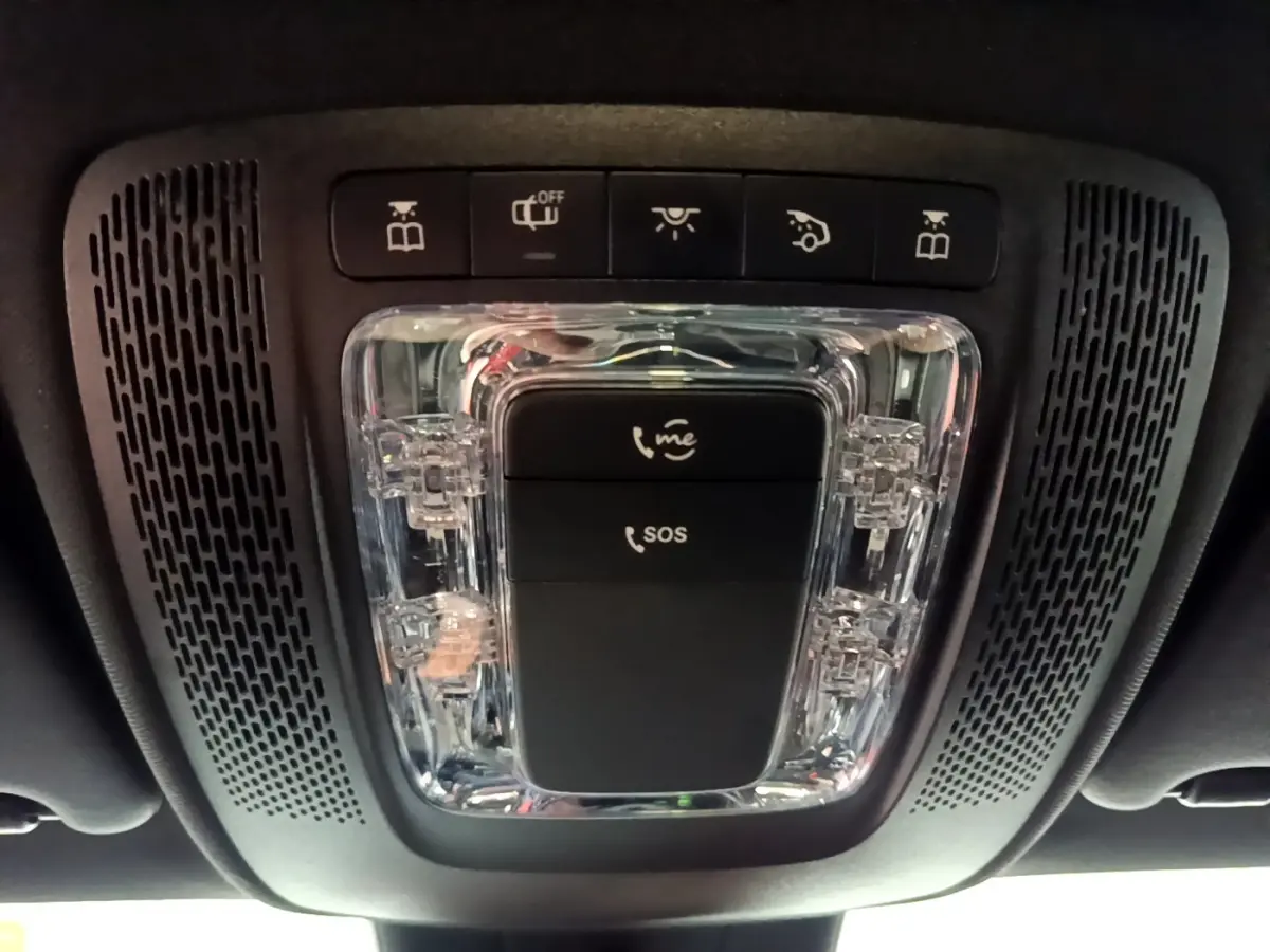 Gros plan sur la console de toit noire avec boutons d'appel d'urgence et éclairage intérieur d'une Mercedes Classe A gris foncé.