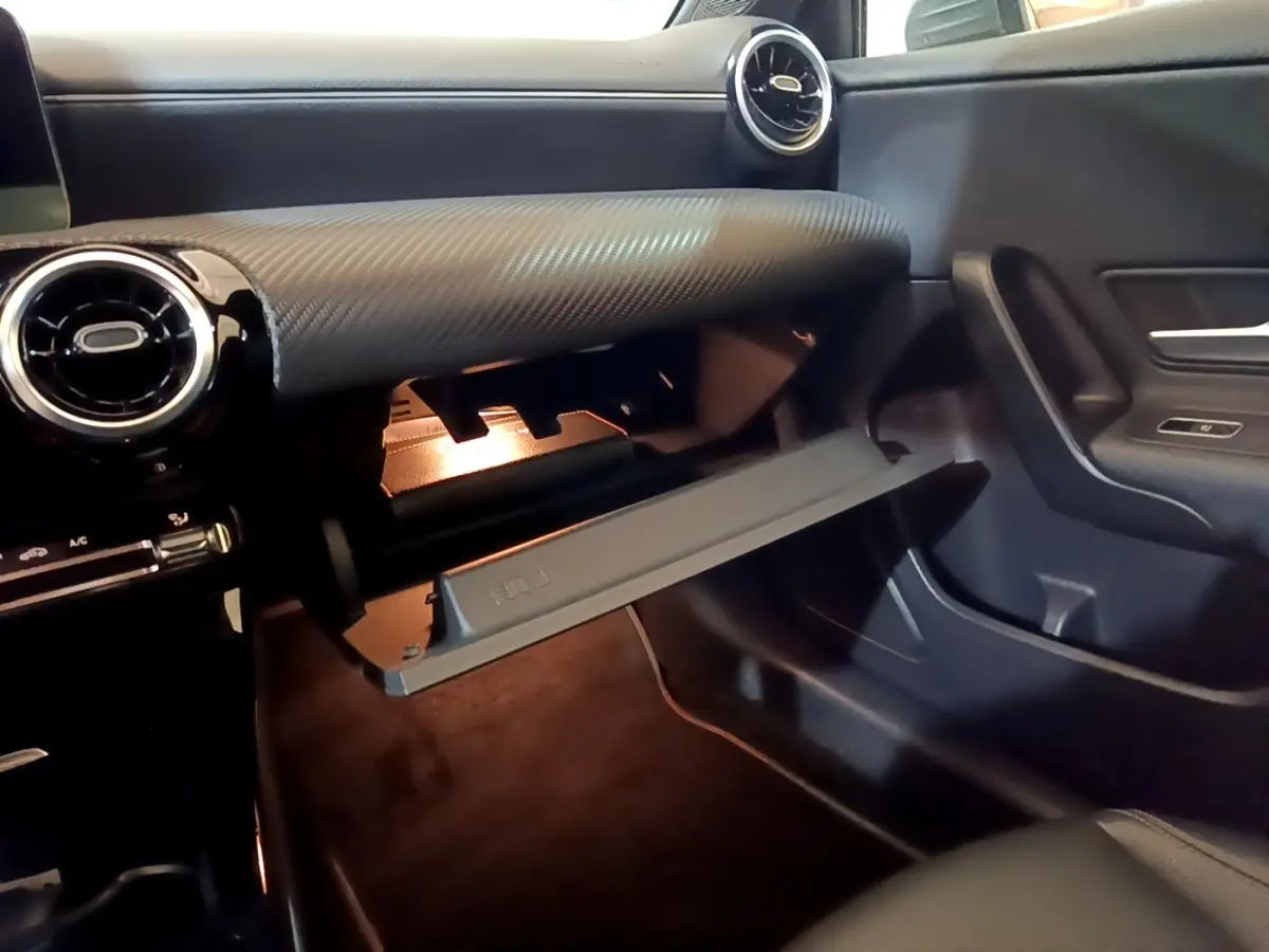 Vue intérieure côté passager de la boîte à gants ouverte, tableau de bord gris foncé texturé de la Mercedes Classe A 180 d 2021.