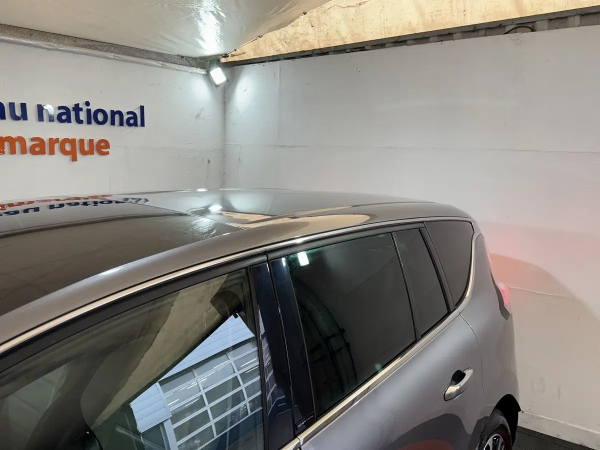 Vue côté droit arrière d’un Renault Espace gris foncé avec vitres arrière teintées dans un garage.