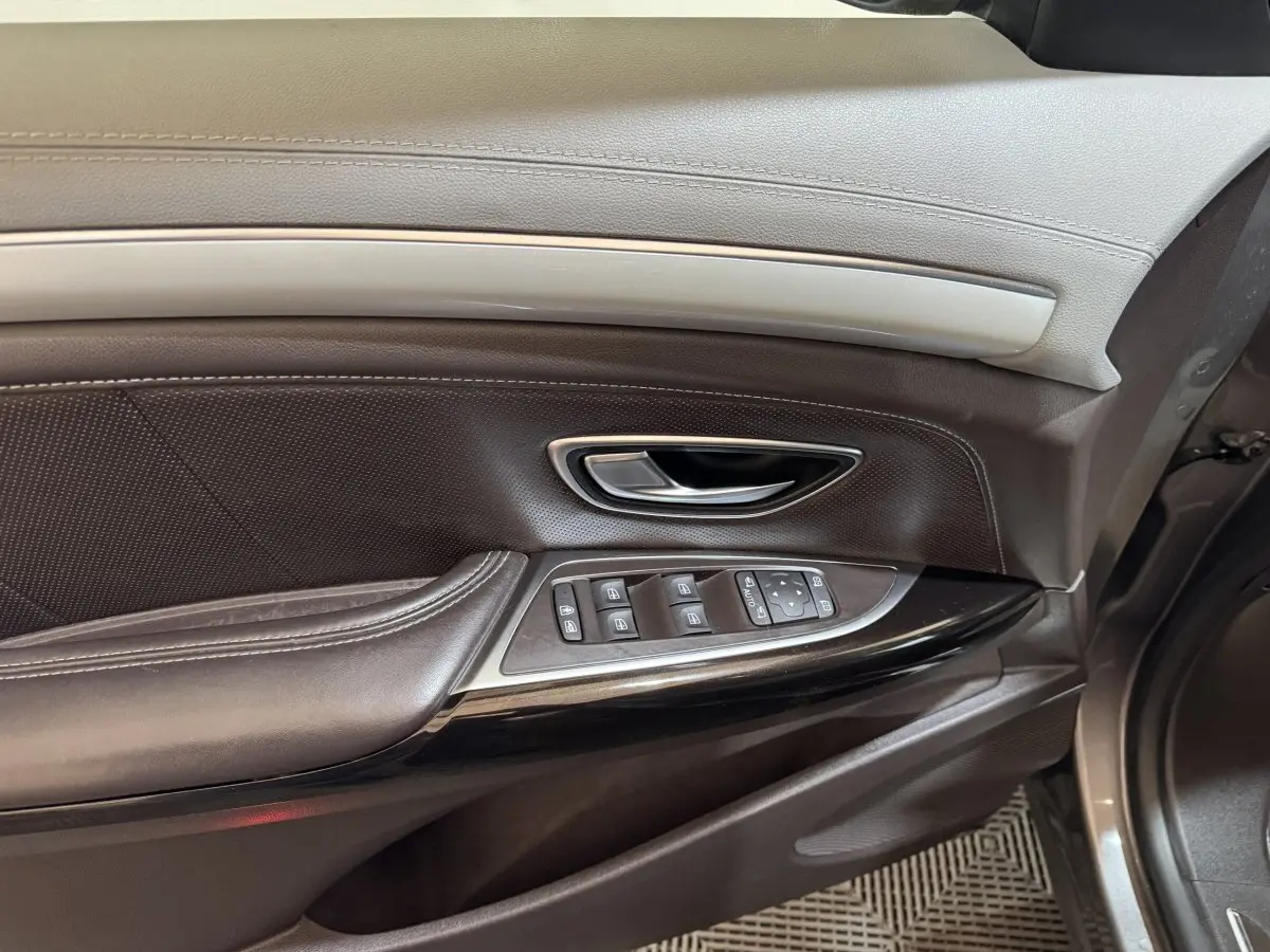 Gros plan sur la porte côté conducteur du Renault Espace gris foncé, montrant les commandes électriques et la poignée intérieure.