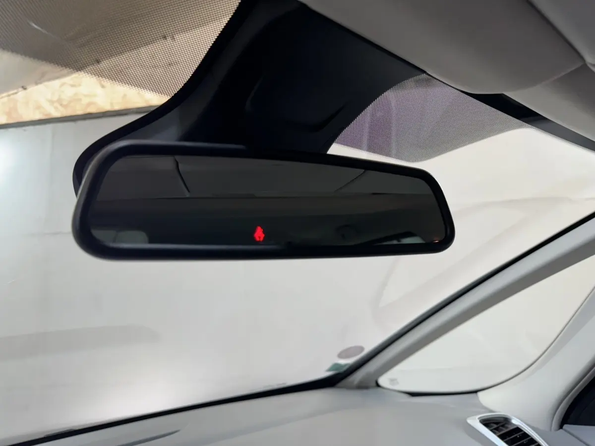 Vue intérieure sur le rétroviseur central d’un Renault Espace gris foncé 2015 avec alerte de ceinture rouge allumée.