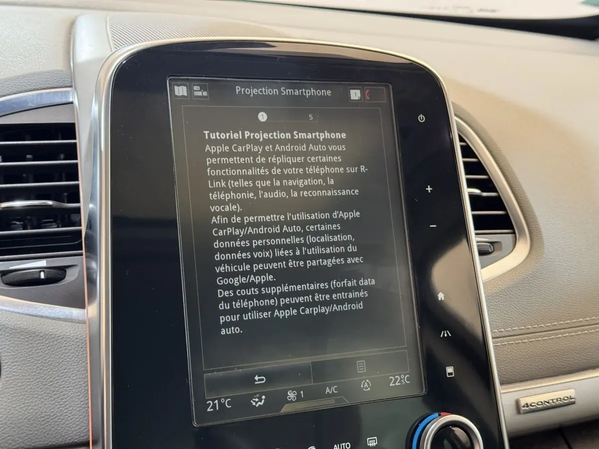 Gros plan sur l'écran tactile central du tableau de bord beige du Renault Espace Initiale Paris 2015 affichant un tutoriel smartphone.