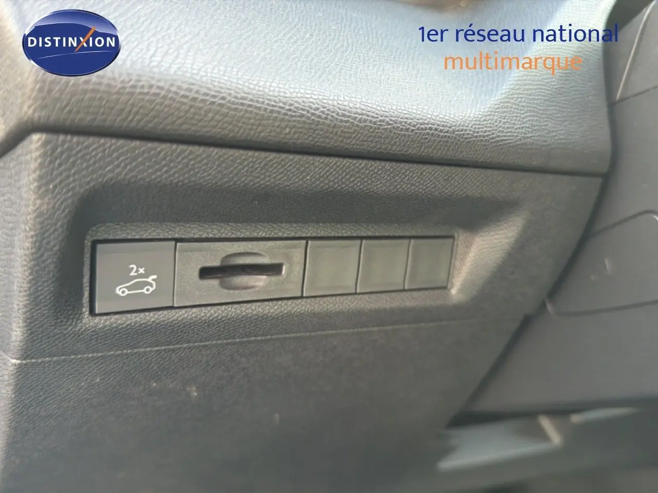 Détail du bouton d'ouverture du coffre sur le tableau de bord noir d'une Peugeot 408 gris selenium metal.