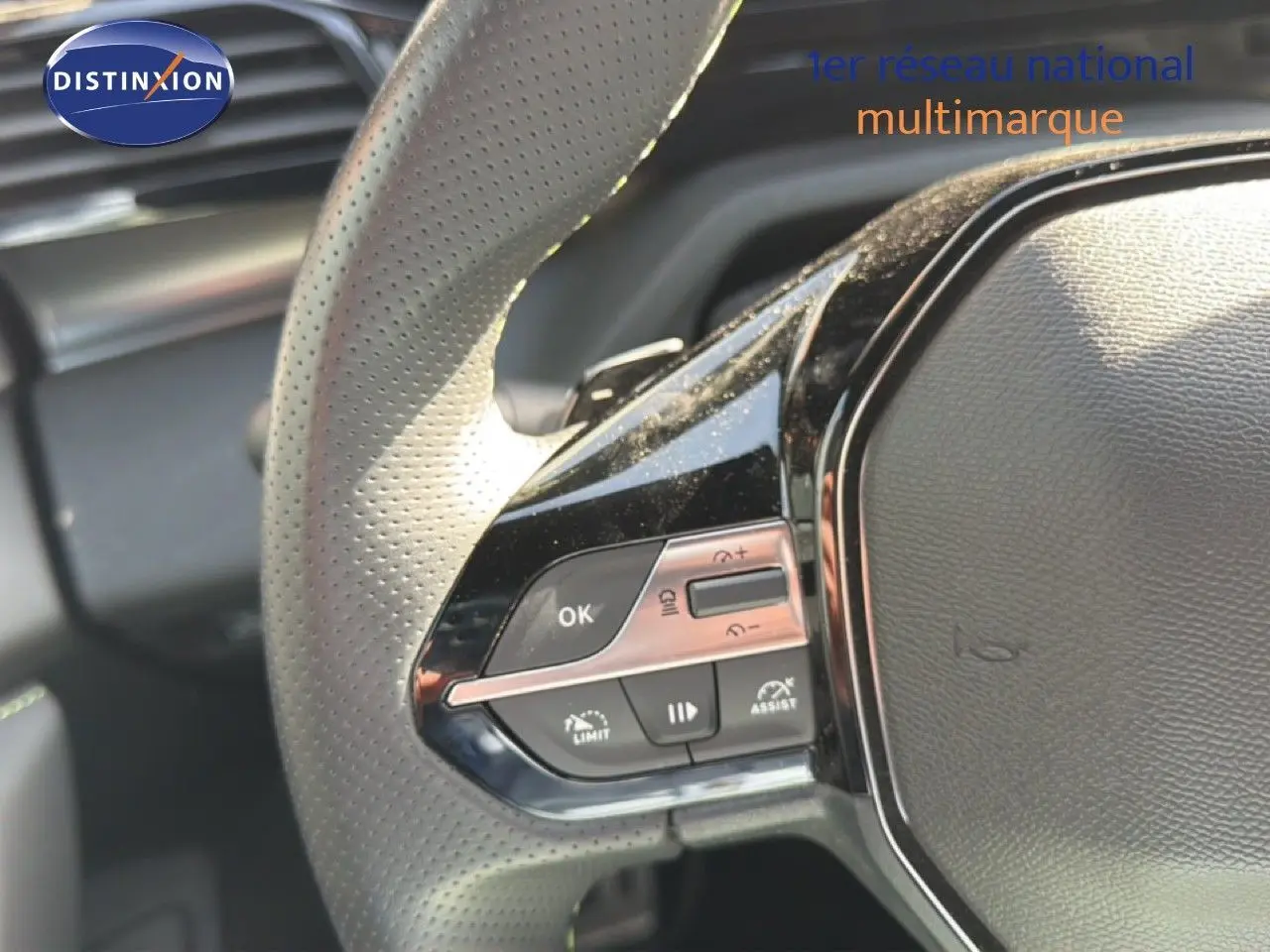 Gros plan sur les commandes multifonctions à gauche du volant perforé d'une Peugeot 408 gris Selenium 2025.