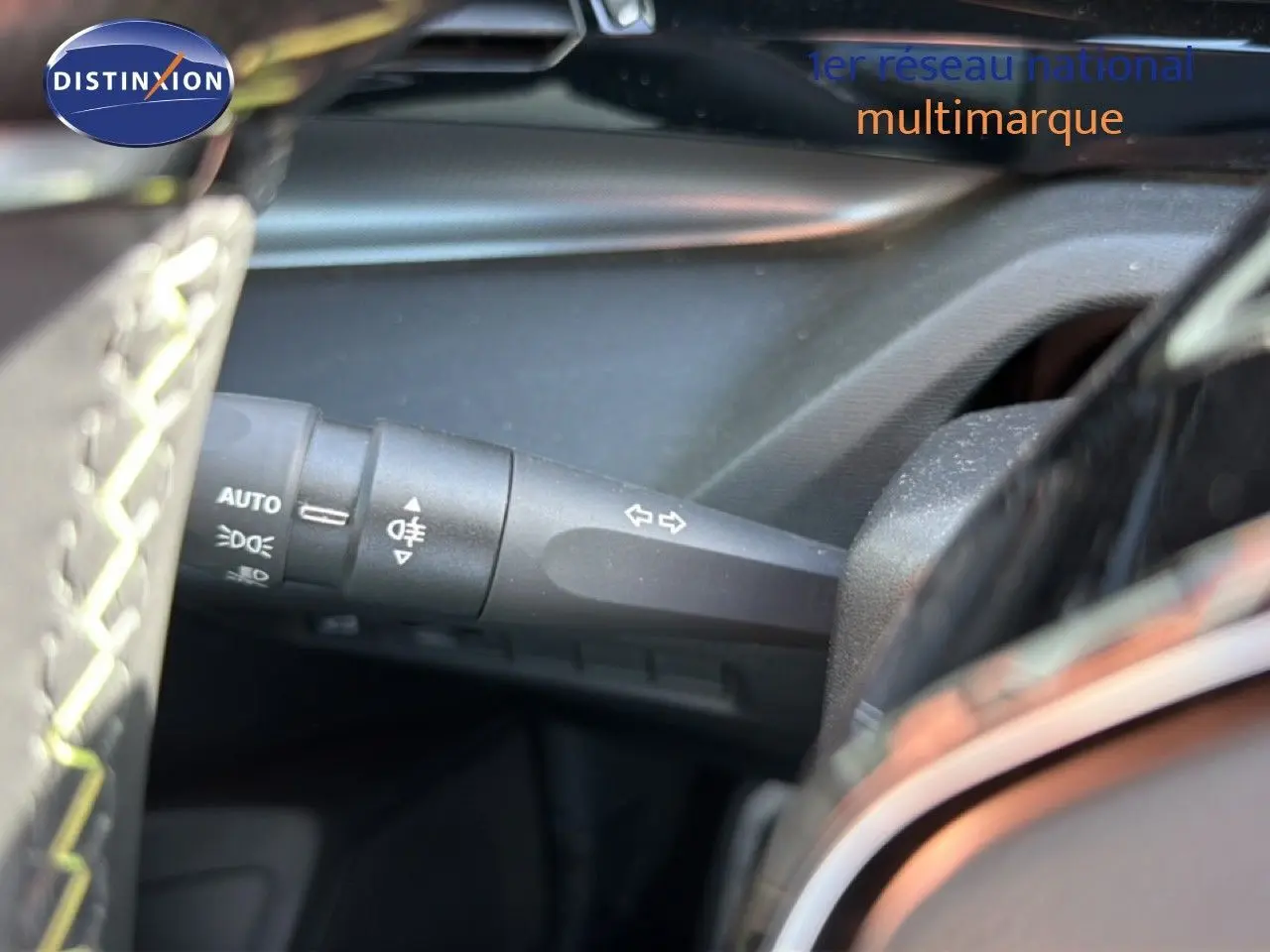 Gros plan sur la commande des clignotants à gauche du volant dans l’habitacle sombre d’une Peugeot 408 gris selenium.