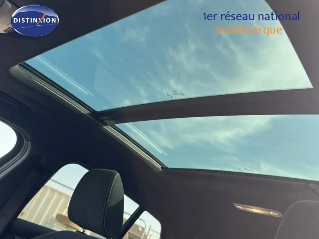 Toit ouvrant panoramique vu de l'intérieur d'une BMW X2 blanc, avec ciel visible à travers le verre.