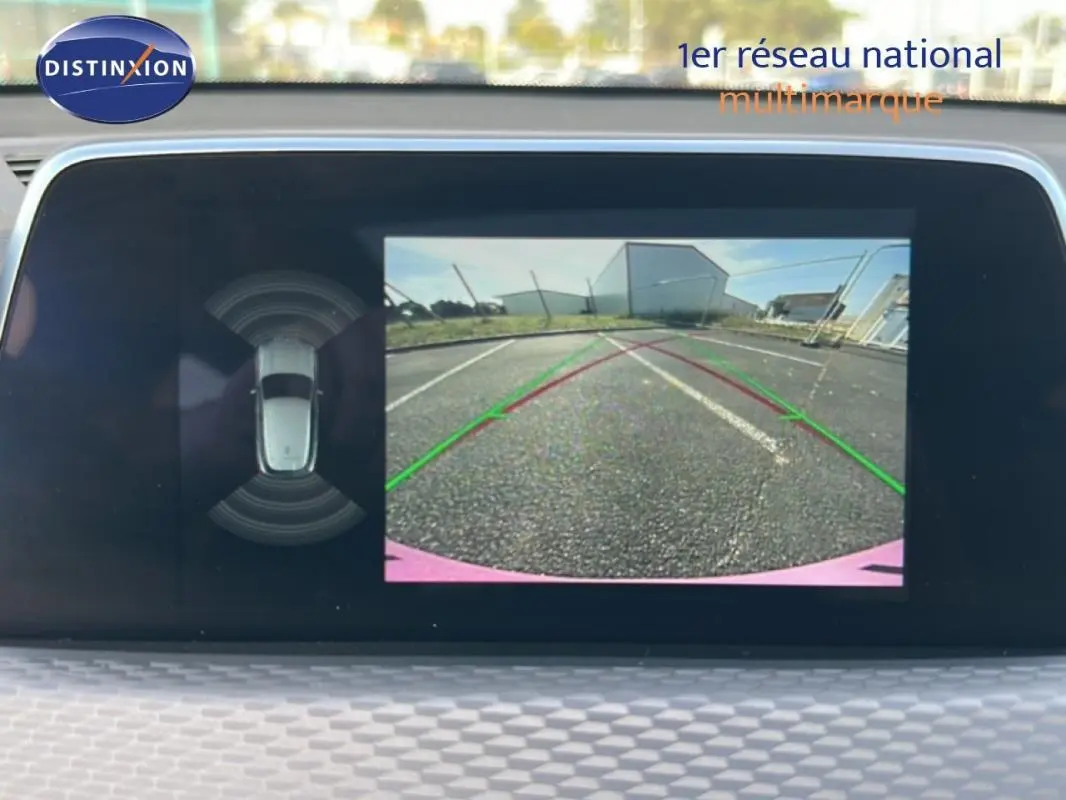Écran de caméra de recul de BMW X2 blanc montrant l’arrière avec lignes de guidage et vue 360° du véhicule.