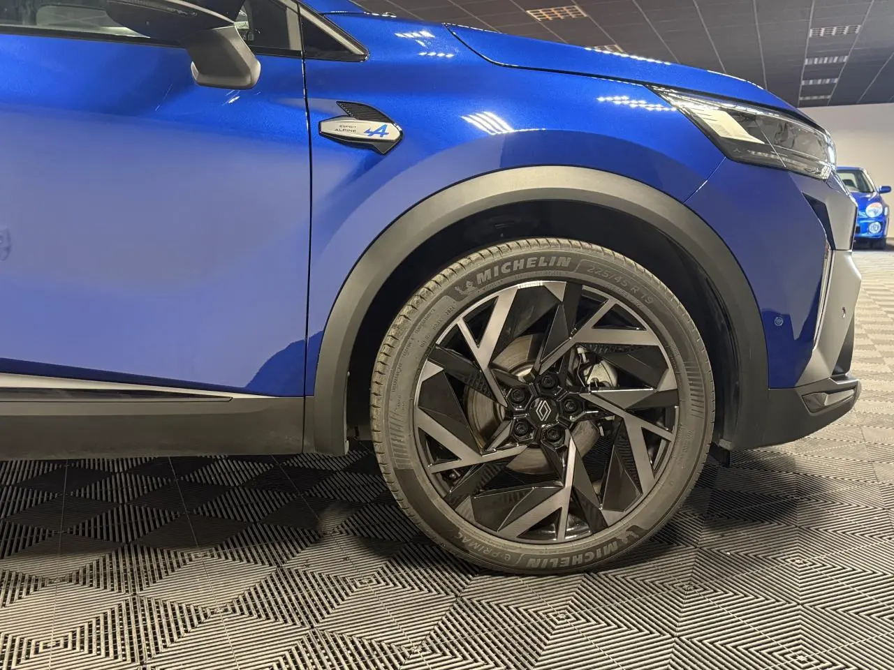Gros plan sur la roue avant droite et l’aile bleu Iron d’un Renault SYMBIOZ Esprit Alpine avec jante aluminium 19 pouces.