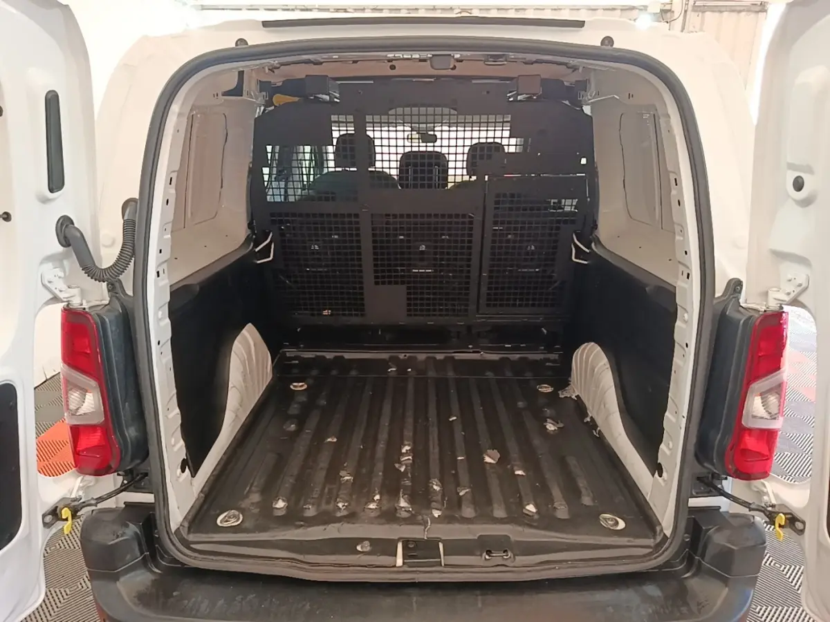 Vue arrière du Peugeot Partner blanc 2020, montrant l’espace de chargement vide avec cloison grillagée pleine.