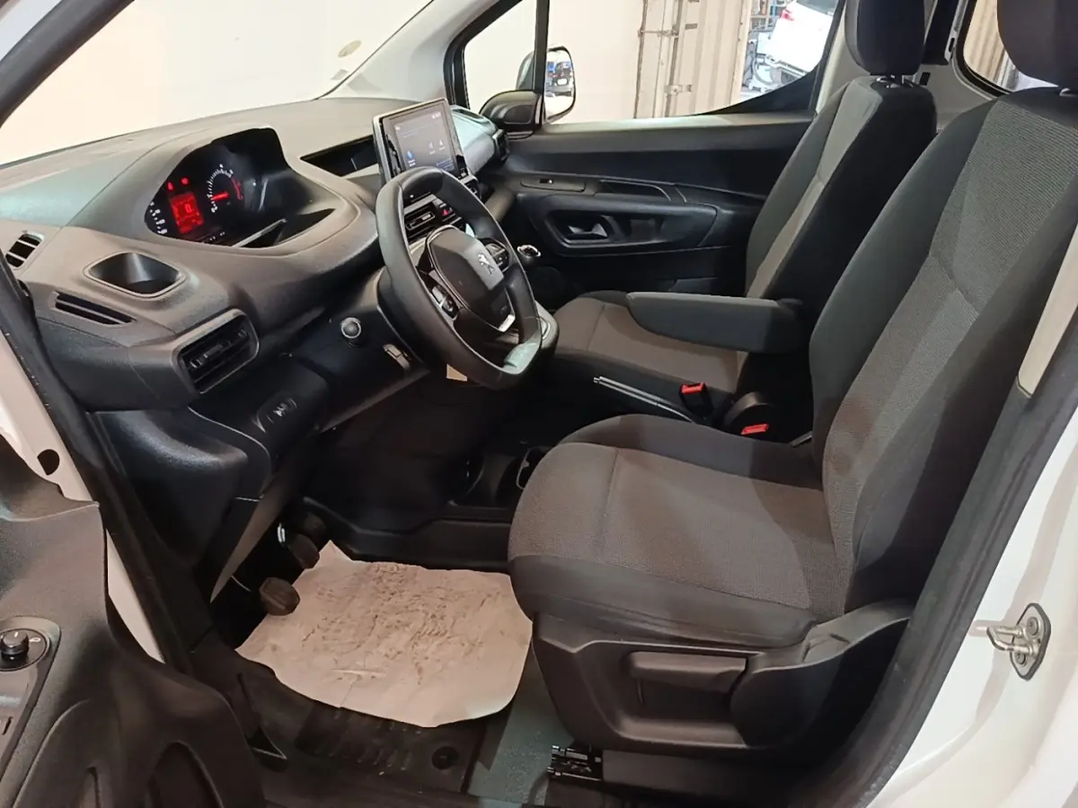 Vue intérieure côté conducteur du Peugeot Partner blanc 2020, montrant le tableau de bord et les sièges avant gris.
