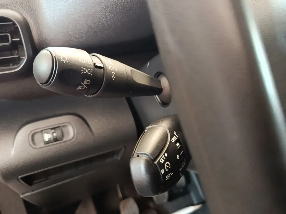 Gros plan sur les commandes de phares et régulateur de vitesse derrière le volant du Peugeot Partner blanc de 2020.