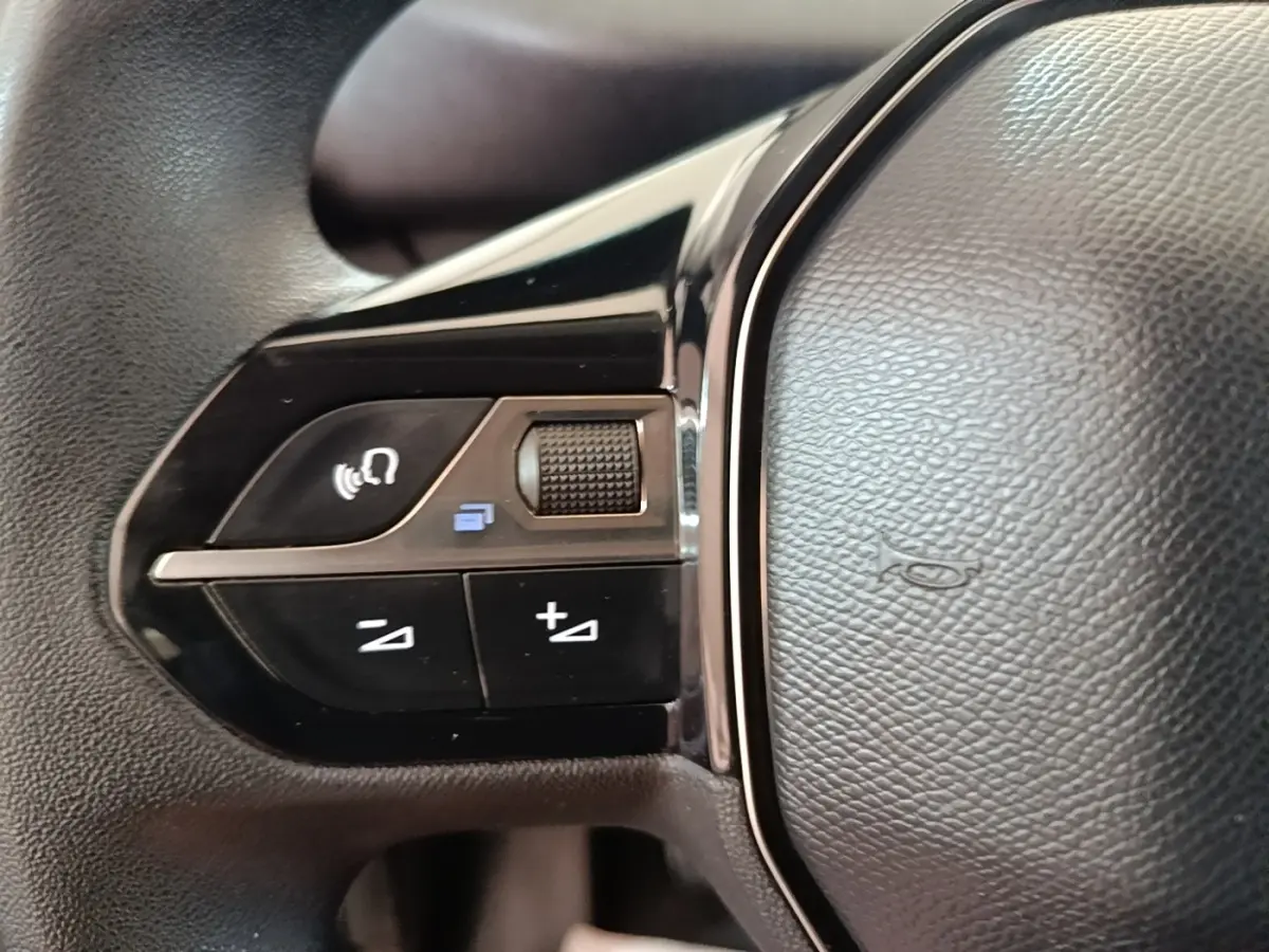 Gros plan sur les commandes gauche du volant noir du Peugeot Partner blanc, version BlueHDi 100 S&S Long Cabine App 2020.