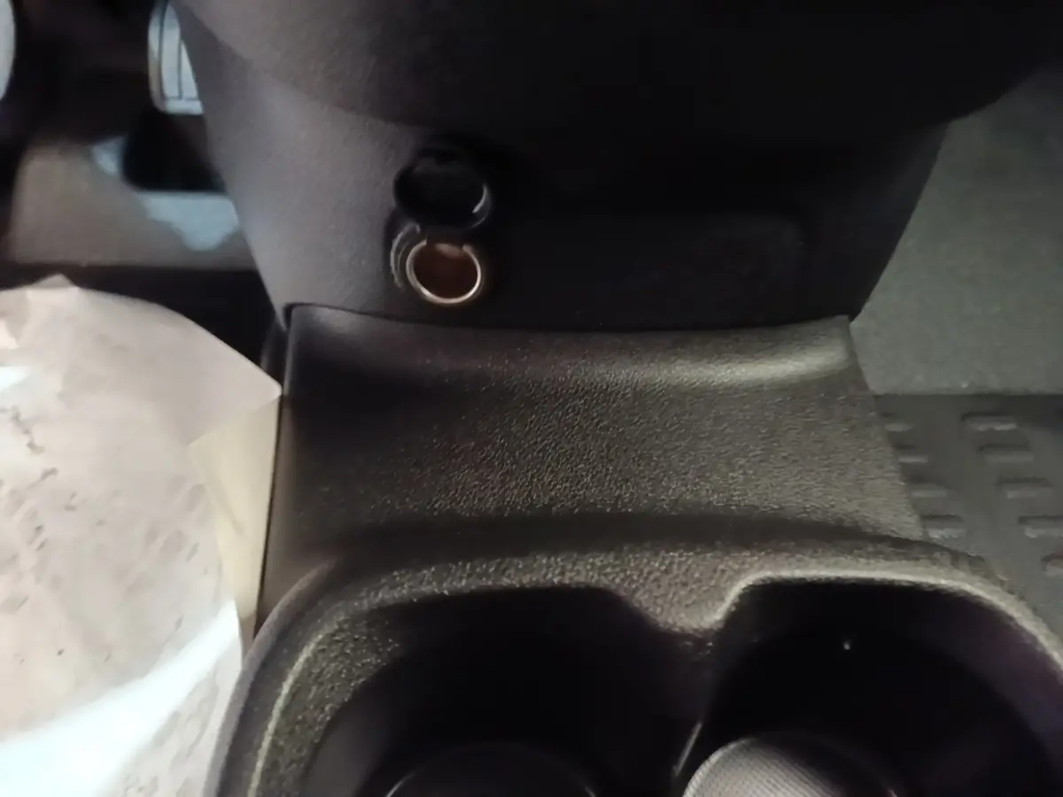 Gros plan sur la prise 12V et porte-gobelets noirs au centre de la console d'un Peugeot Partner blanc 2020.