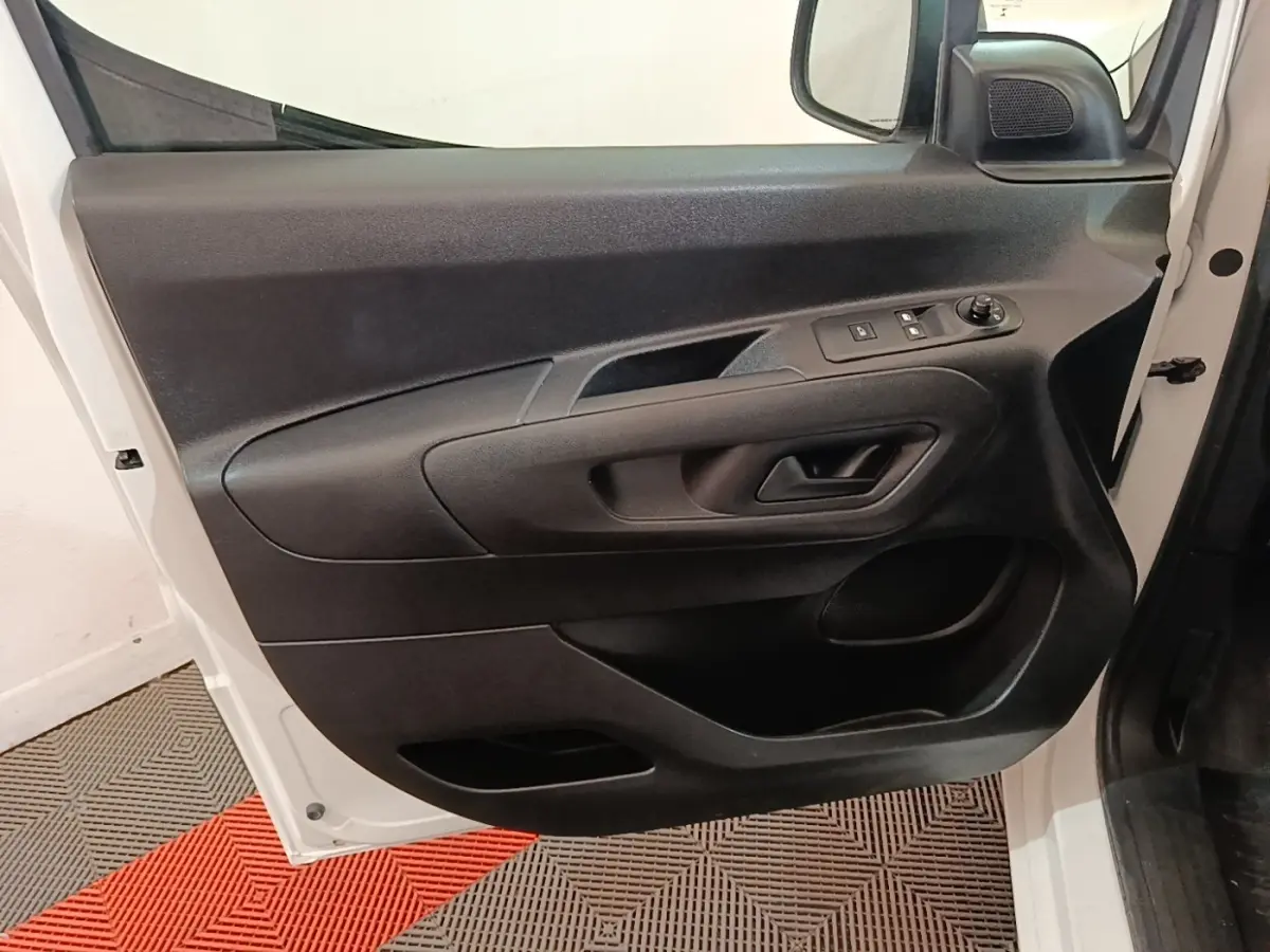 Vue rapprochée de la porte avant gauche noire à l'intérieur du Peugeot Partner blanc, avec commandes électriques des vitres.