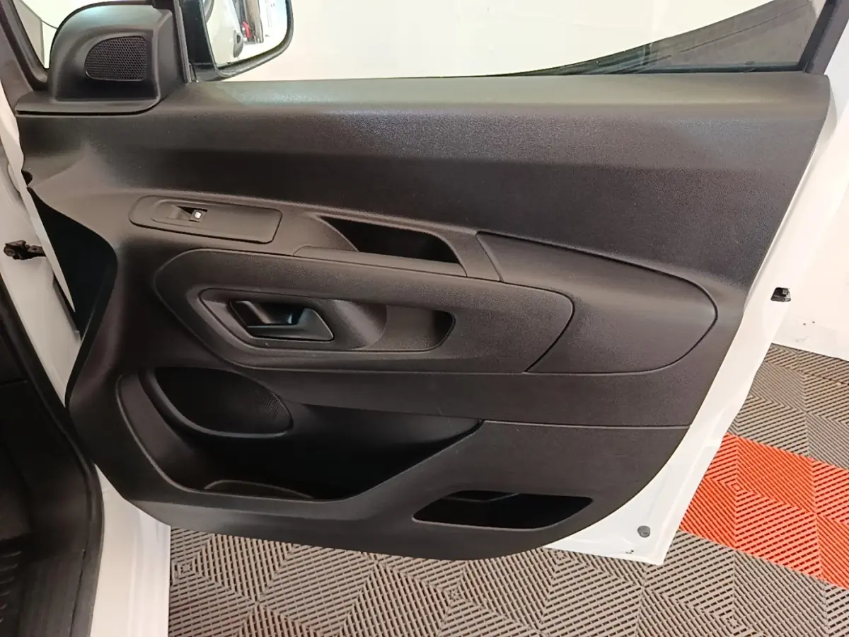 Vue rapprochée de la porte avant gauche noire avec poignée et commande de vitre du Peugeot Partner blanc 2020.