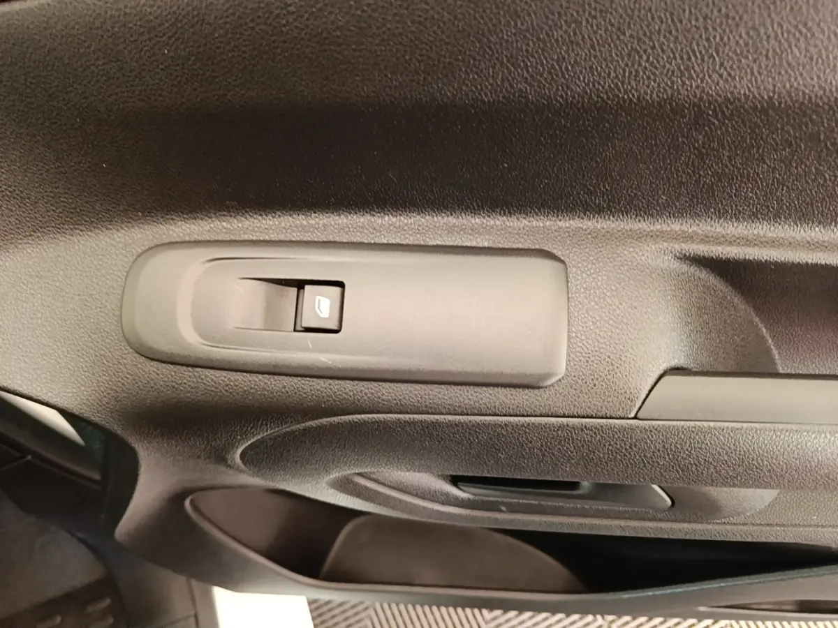 Gros plan sur la commande de lève-vitre côté conducteur dans l'intérieur noir du Peugeot Partner blanc 2020.
