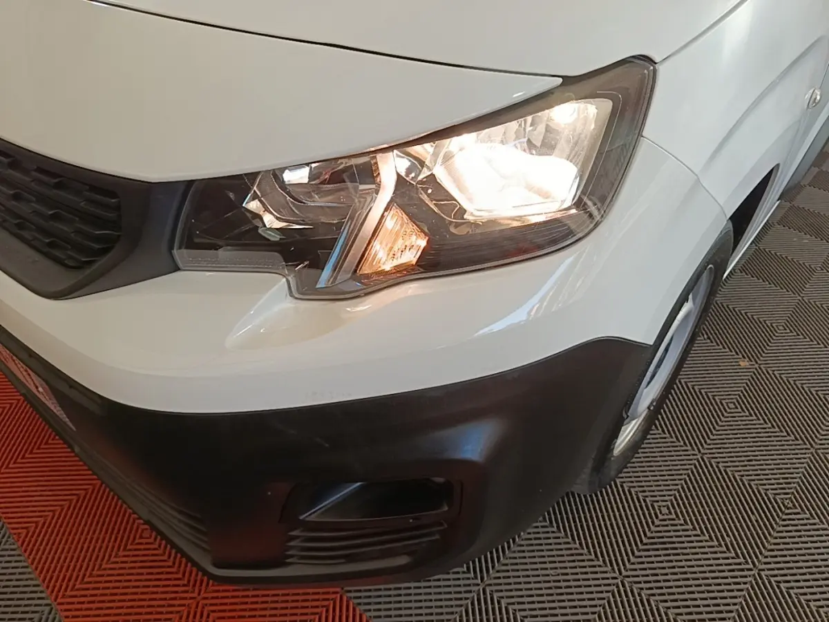 Gros plan sur l'avant droit blanc du Peugeot Partner 2020 avec phare allumé et pare-chocs noir mat.