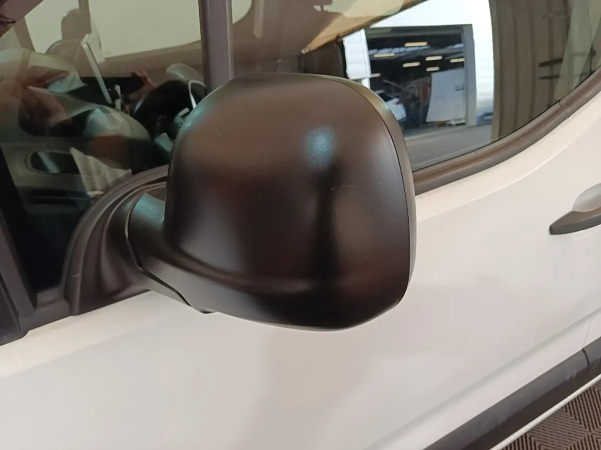 Gros plan sur le rétroviseur noir côté conducteur du Peugeot Partner blanc, vue latérale avant.