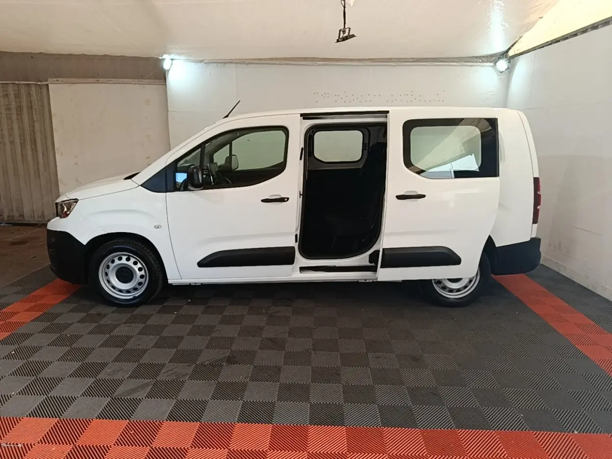 Vue latérale droite d'un Peugeot Partner blanc 2020 avec porte coulissante ouverte en intérieur.