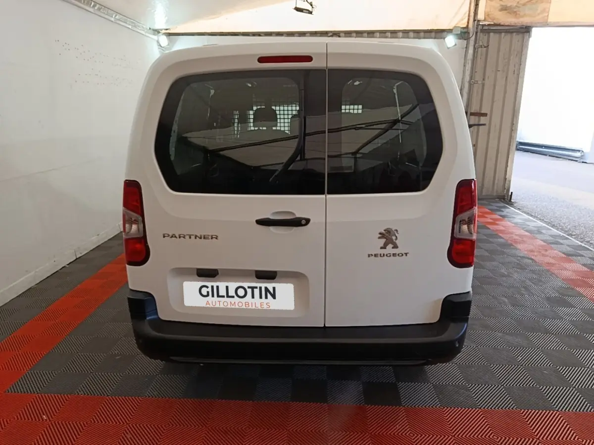Vue arrière d'un Peugeot Partner blanc 2020 avec portes battantes et logo visible en garage.